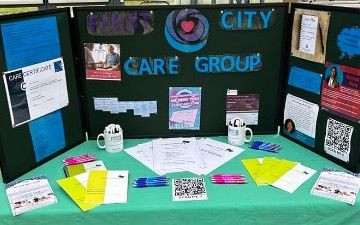 Image of recruitment resources from First City Care Group - including pink and blue ballpoint pens and booklets set out on a green table cloth